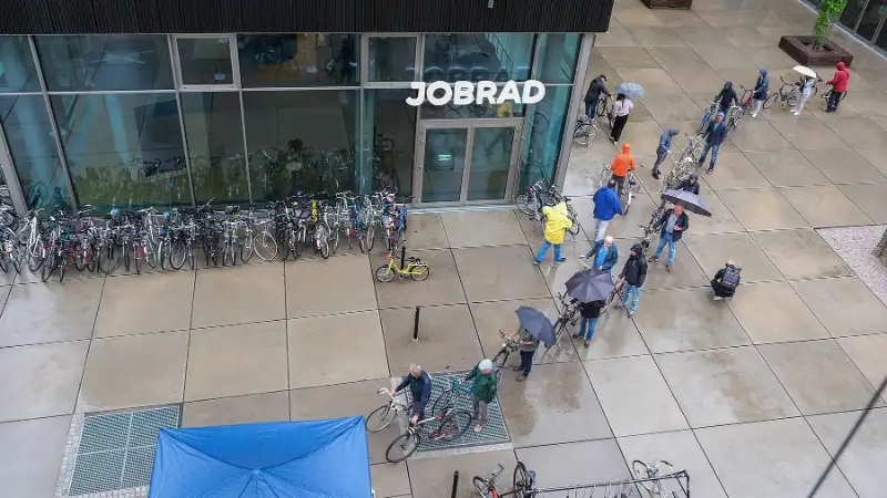 Eine lange Schlange von Menschen mit Fahrrädern und Regenschirmen auf dem JobRad Campus