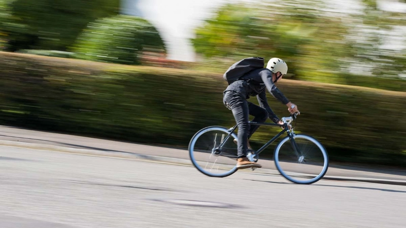 Ein Radfahrer mit Helm fährt schnell eine Straße herunter